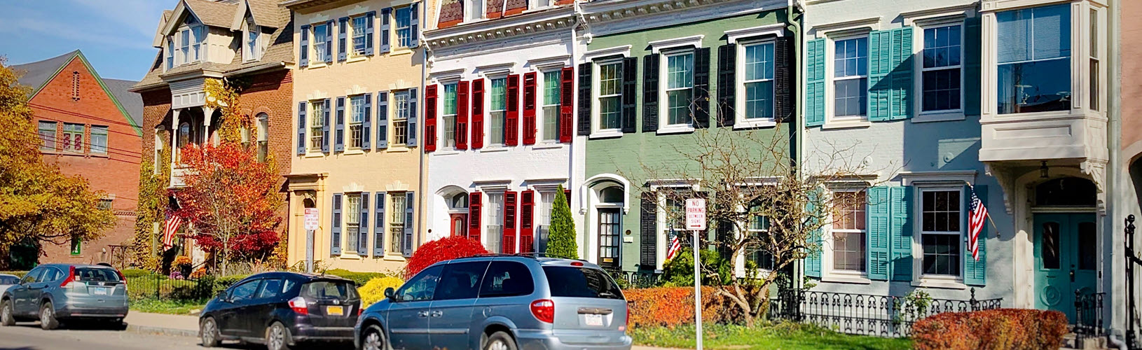 Picture of colorful town houses with three vehicles parked in the front in Geneva, NY.
