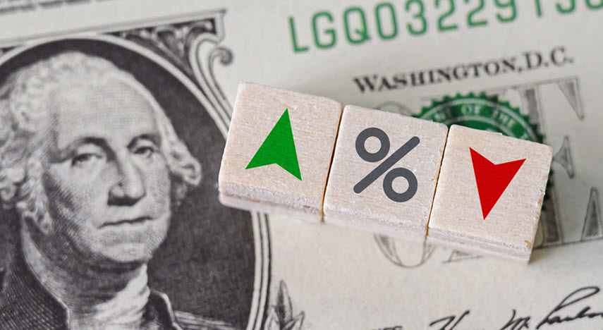 Three blocks on top of a one dollar bill. The blocks have a green arrow point up, precent sign, and a red arrow pointing down, respectively.