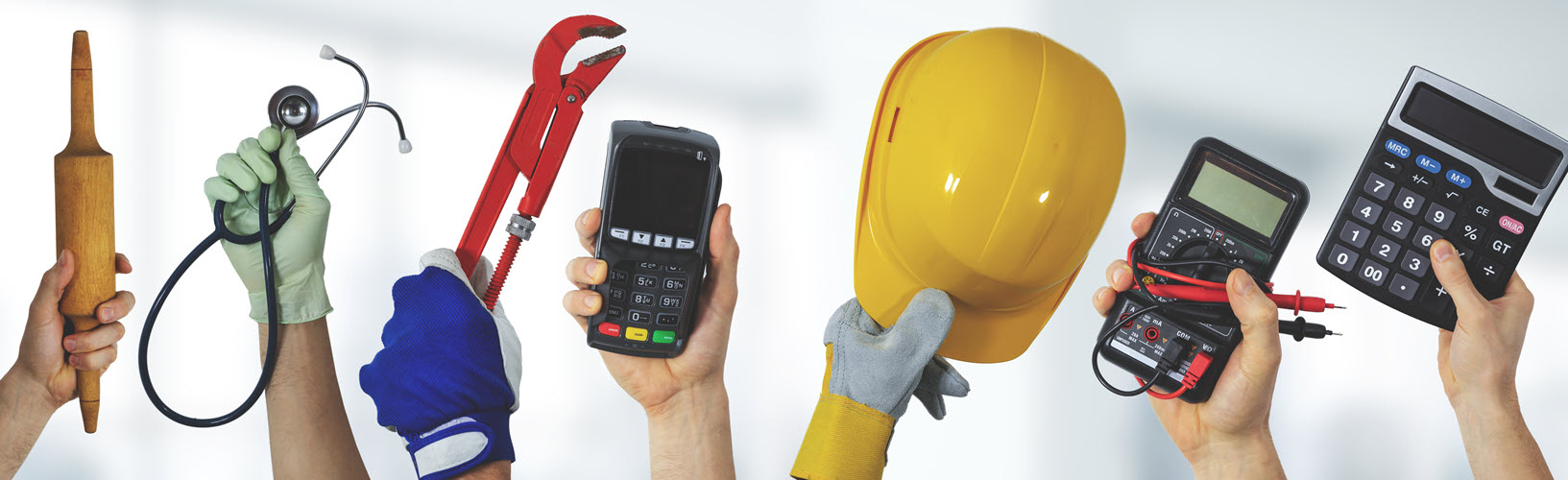 Hands holding up tools of multiple professions against a white background: rolling pin, stethoscope, wrench, card reader, hardhat, multimeter, and a calculator.