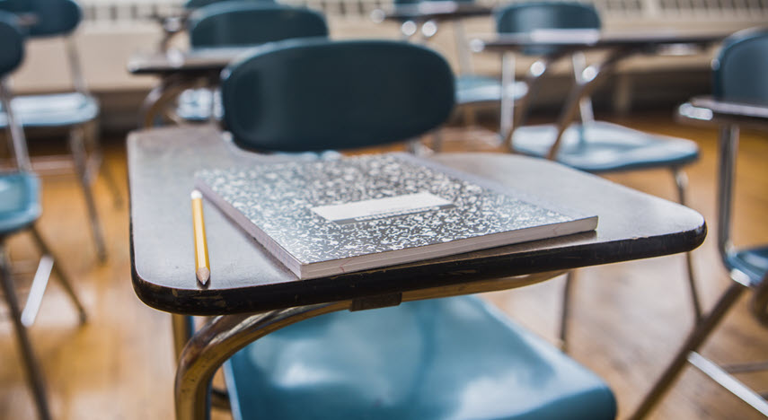 School desk with journal and pencil on top.