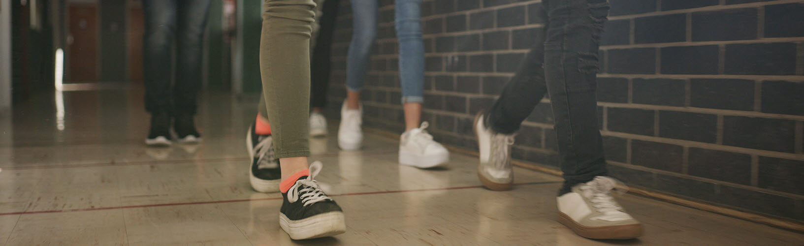 Legs of students walking through a school hallway.