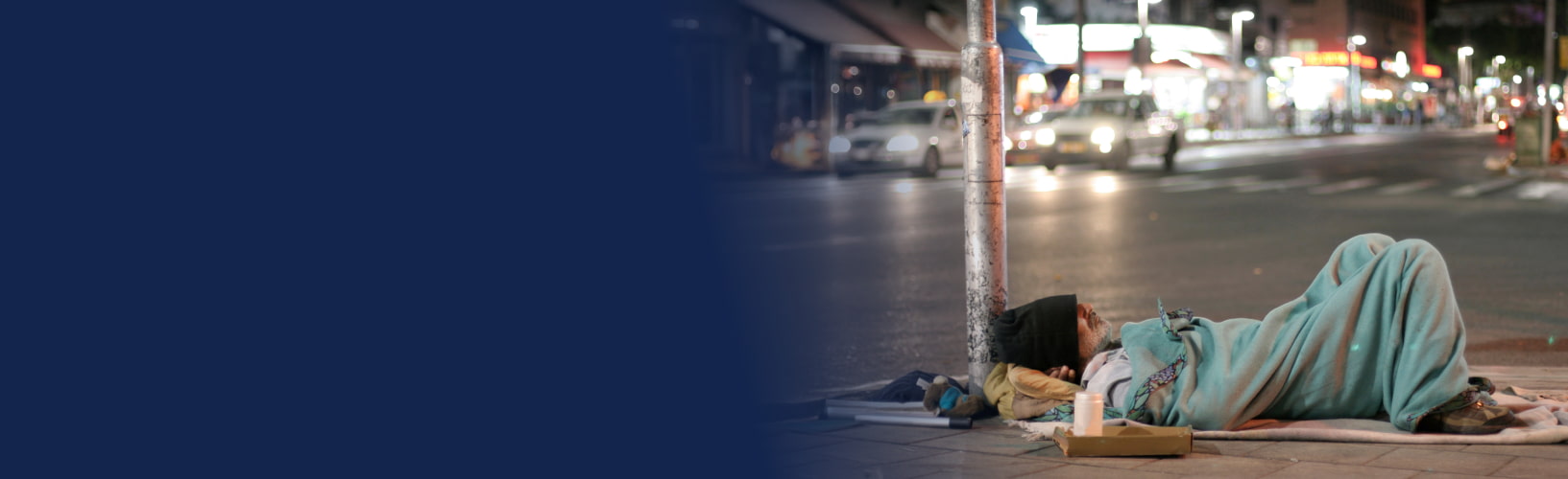 a man experiencing homelessness sleeping on a busy sidewalk