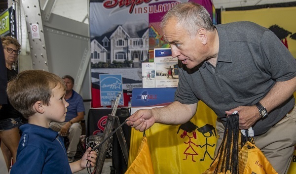 Comptroller DiNapoli handing a bag to a young child.