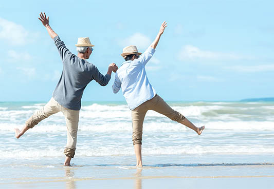 senior couple jumping on the beach in excitement