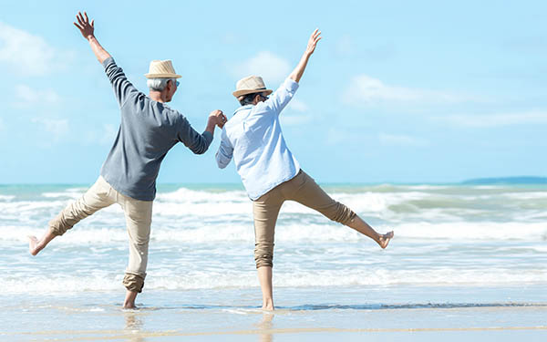 senior couple jumping on the beach in excitement