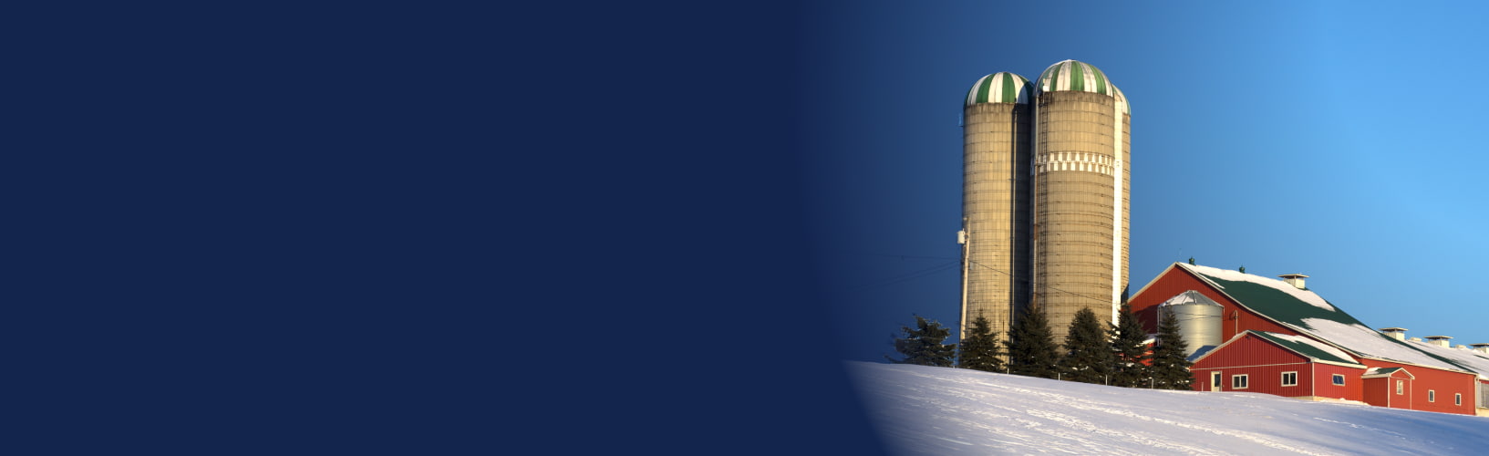 a snow covered farm with a red barn and hay bales