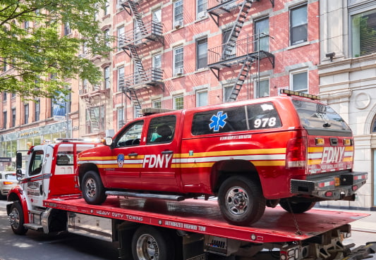a new york city fire department vehicle sits on the bed of a tow truck