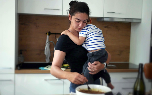 mother holding baby while cooking stew