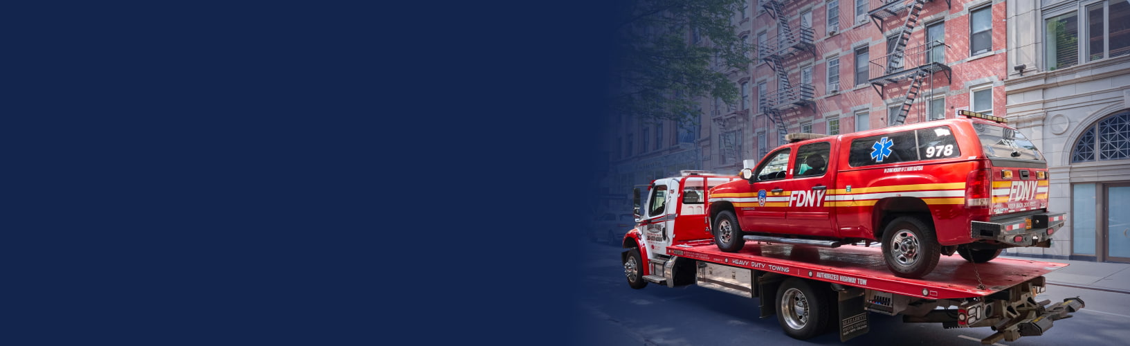 a new york city fire department vehicle sits on the bed of a tow truck