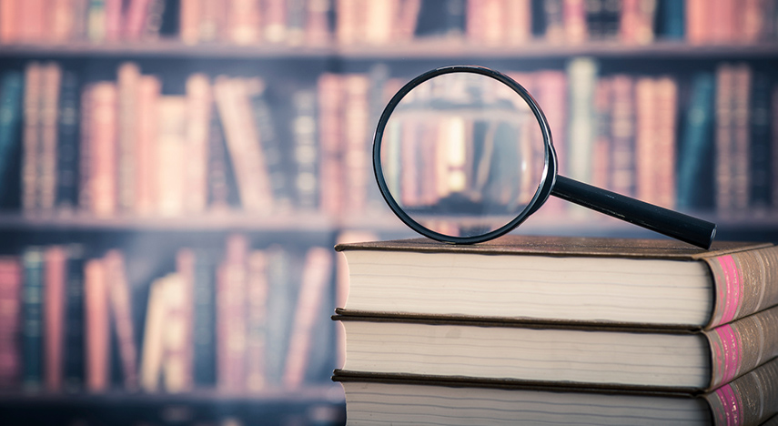 Magnifying glass on stack of books.