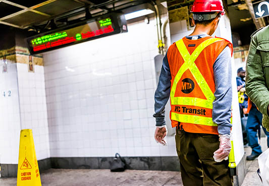metropolitan transportation authority employee inspecting leak in underground transit on empty large platform in new york city subway station