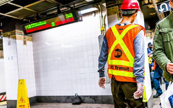 metropolitan transportation authority employee inspecting leak in underground transit on empty large platform in new york city subway station