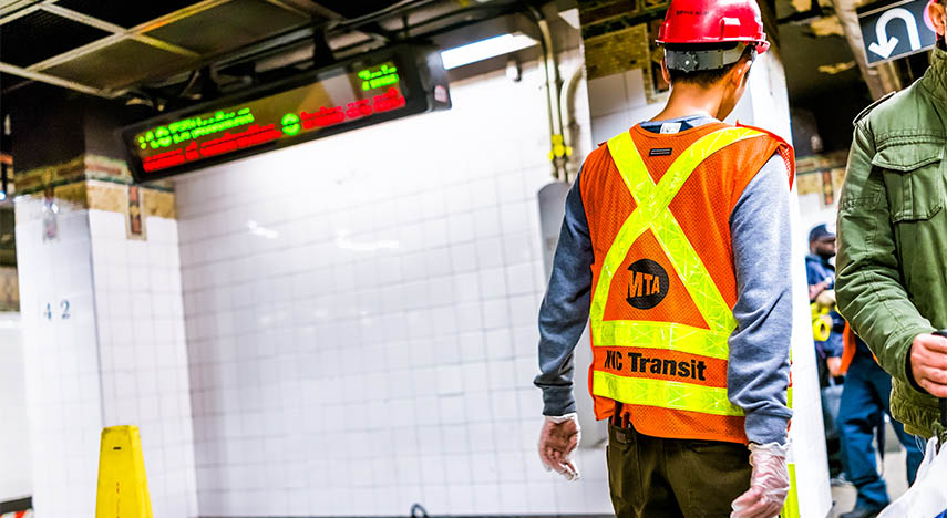 metropolitan transportation authority employee inspecting leak in underground transit on empty large platform in new york city subway station
