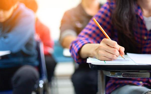 high school student sitting in a classroom writing with a pencil