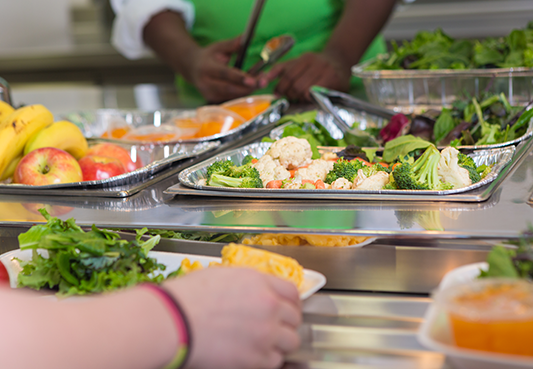 student receives a selection of healthy foods in school cafeteria line