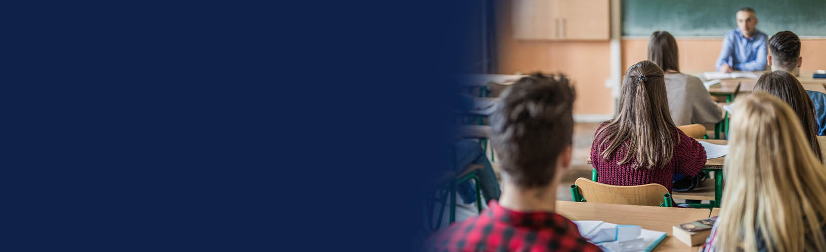 Students sitting at desks in a classroom looking at the teacher