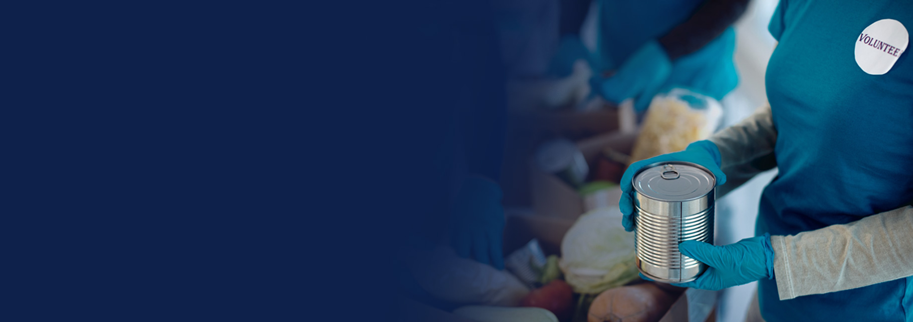 volunteer at food pantry packing boxes of groceries in an assembly line of other volunteers