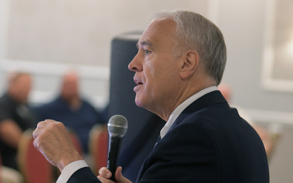 State Comptroller Thomas P. DiNapoli standing at a podium addressing a room filled with people.