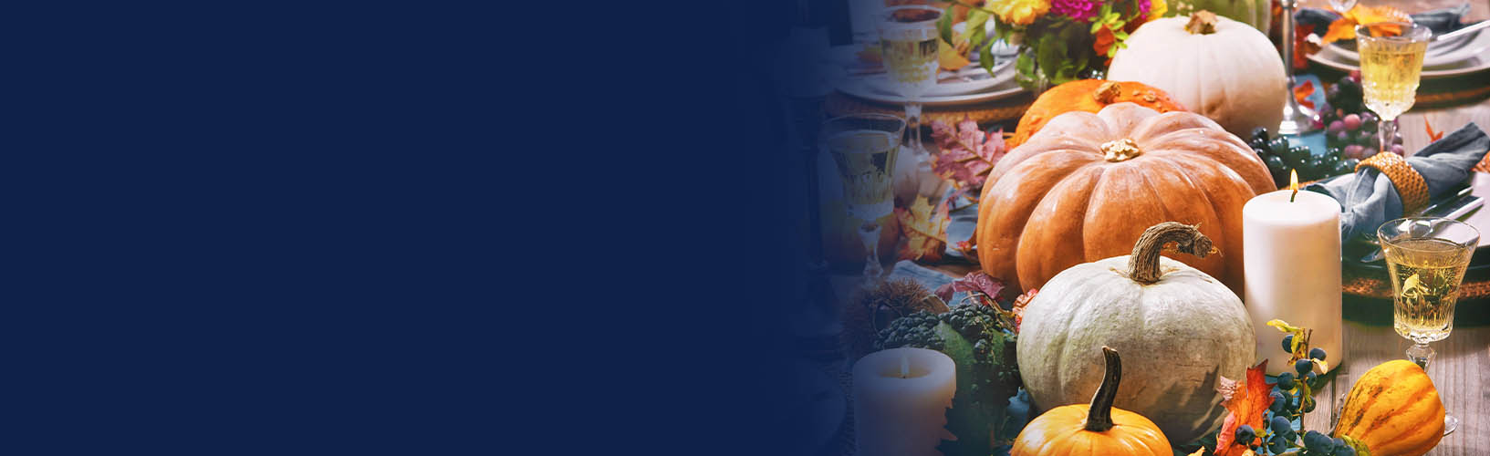 a thanksgiving tablescape of candles, flowers, gourds, and leaves