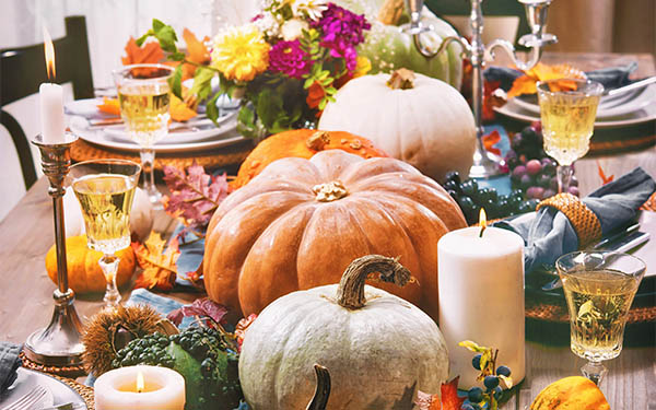 a thanksgiving tablescape of candles, flowers, gourds, and leaves