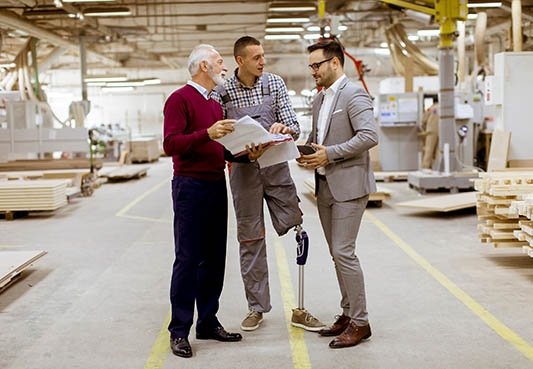 Workers with disabilities reviewing a report in a warehouse.