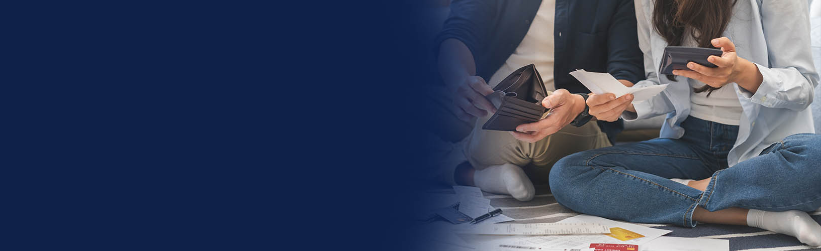 Young adults sitting on the floor holding wallets while looking at bills on the floor