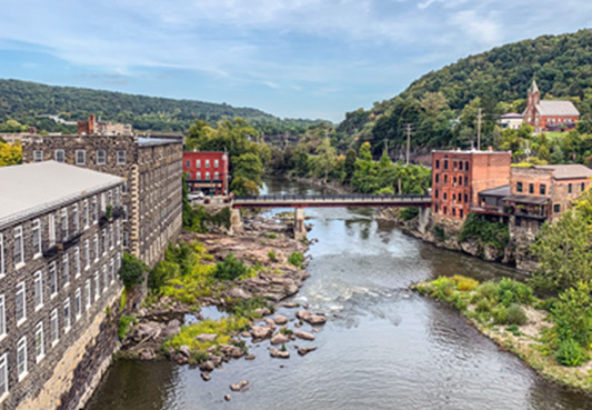buildings lined up on each side of a river with mountains in the background