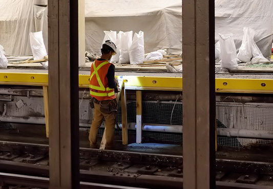 worker standing next to subway tracks