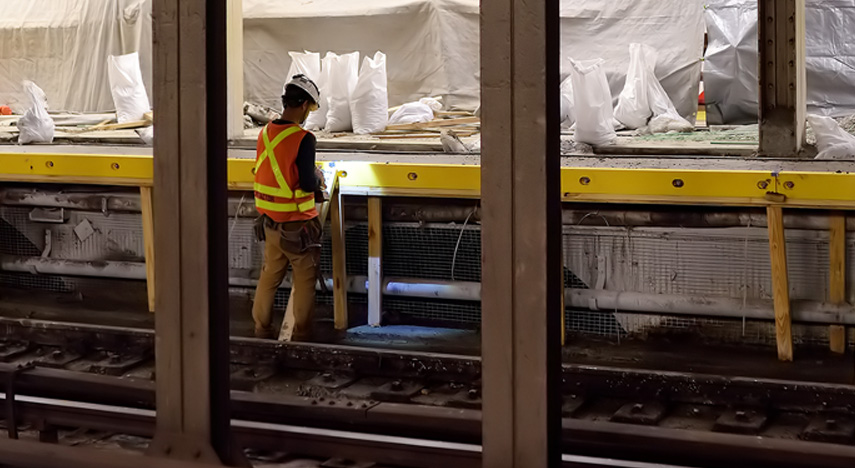 worker standing next to subway tracks