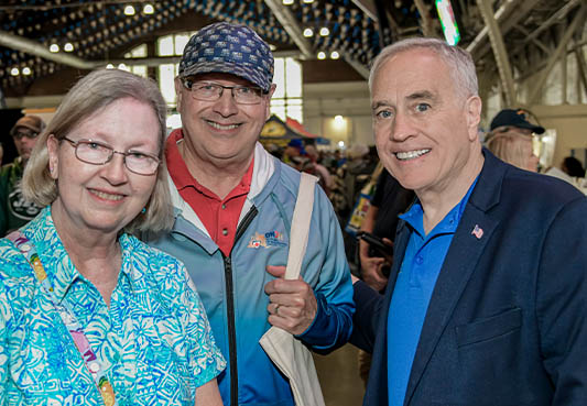Comptroller Thomas P. DiNapoli posing for a photo with two adults
