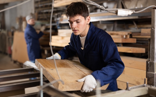 Young person working on a table saw in a commercial woodshop.