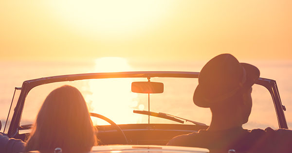couple looking at sunset from convertible