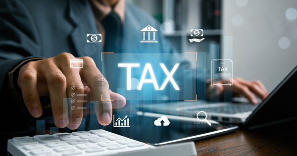 Man using laptop and calculator with the word TAX overlayed