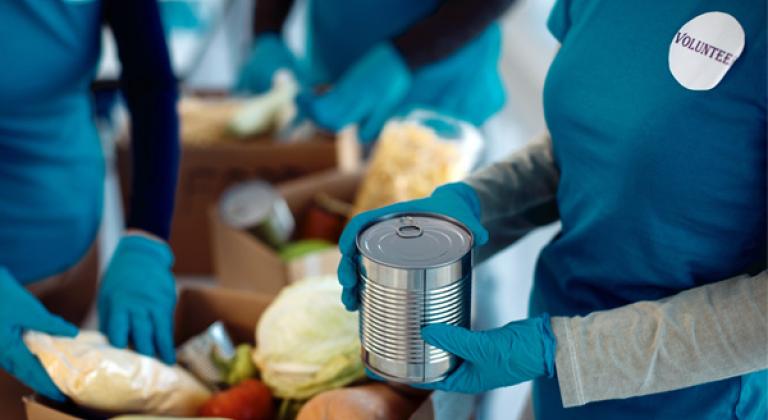volunteer at food pantry packing boxes of groceries in an assembly line of other volunteers