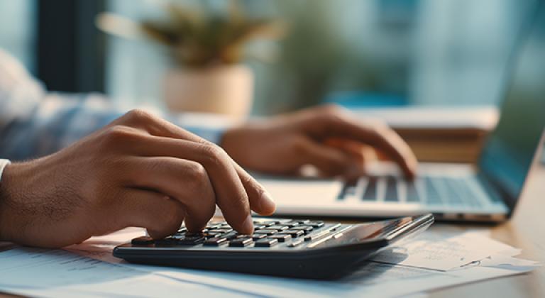 closeup of hands working on laptop and calculator