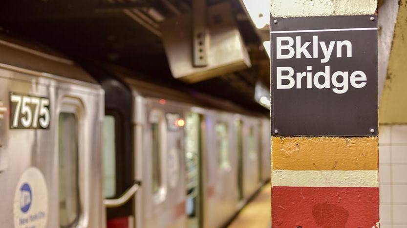 Subway cars next to a sign that says "Bklyn Bridge"