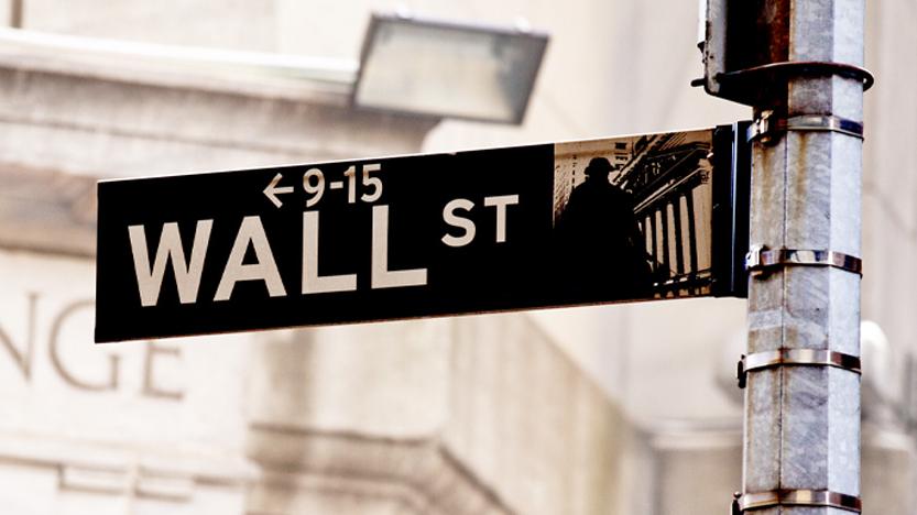 Wall Street sign with the New York stock exchange building in the background.