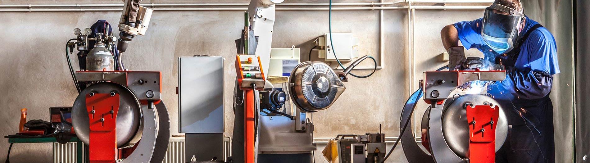 Man and robotic machine work together inside industrial building. 