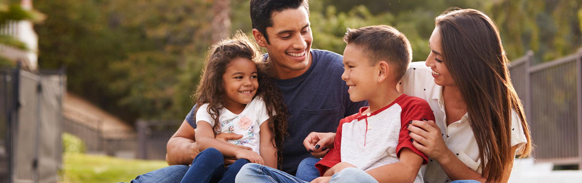 Happy young Hispanic family sitting together in the park.