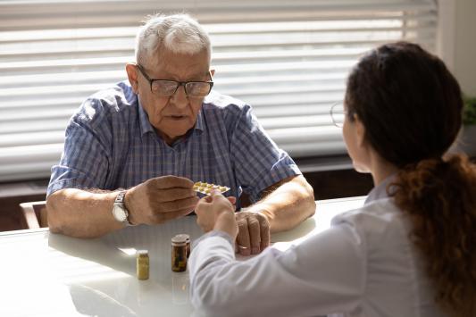 older aged adult being handed medication from medical professional