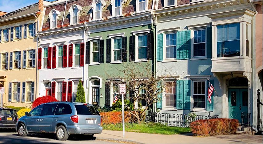 Colorful town houses in Geneva, NY with a van parked on the street.