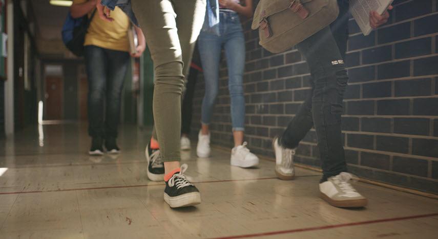 Legs of students walking through a school hallway.