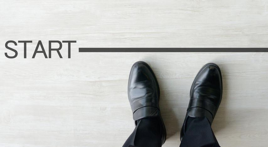 Picture is looking down at a person's dress shoes at a starting line. Line says START.