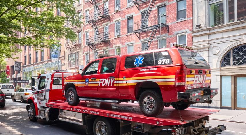a new york city fire department vehicle sits on the bed of a tow truck