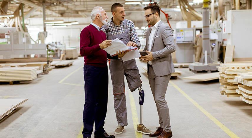 Workers with disabilities reviewing a report in a warehouse.