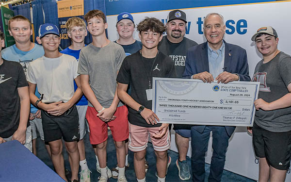 new york state comptroller thomas p. dinapoli and athletes from the onondaga youth hockey association at the new york state fair