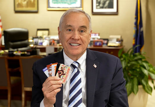 New York State Comptroller Thomas P. DiNapoli holding gift cards