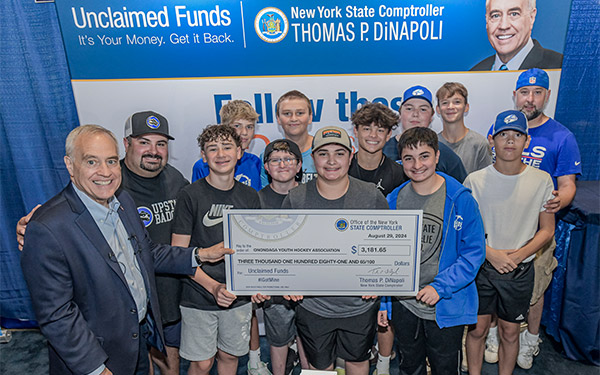 Hockey team holding unclaimed funds check with Comptroller DiNapoli.