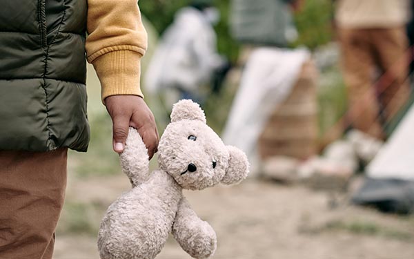 Homeless child holding white teddy bear